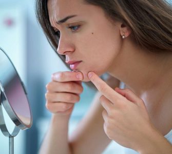mujer mirando acne en espejo